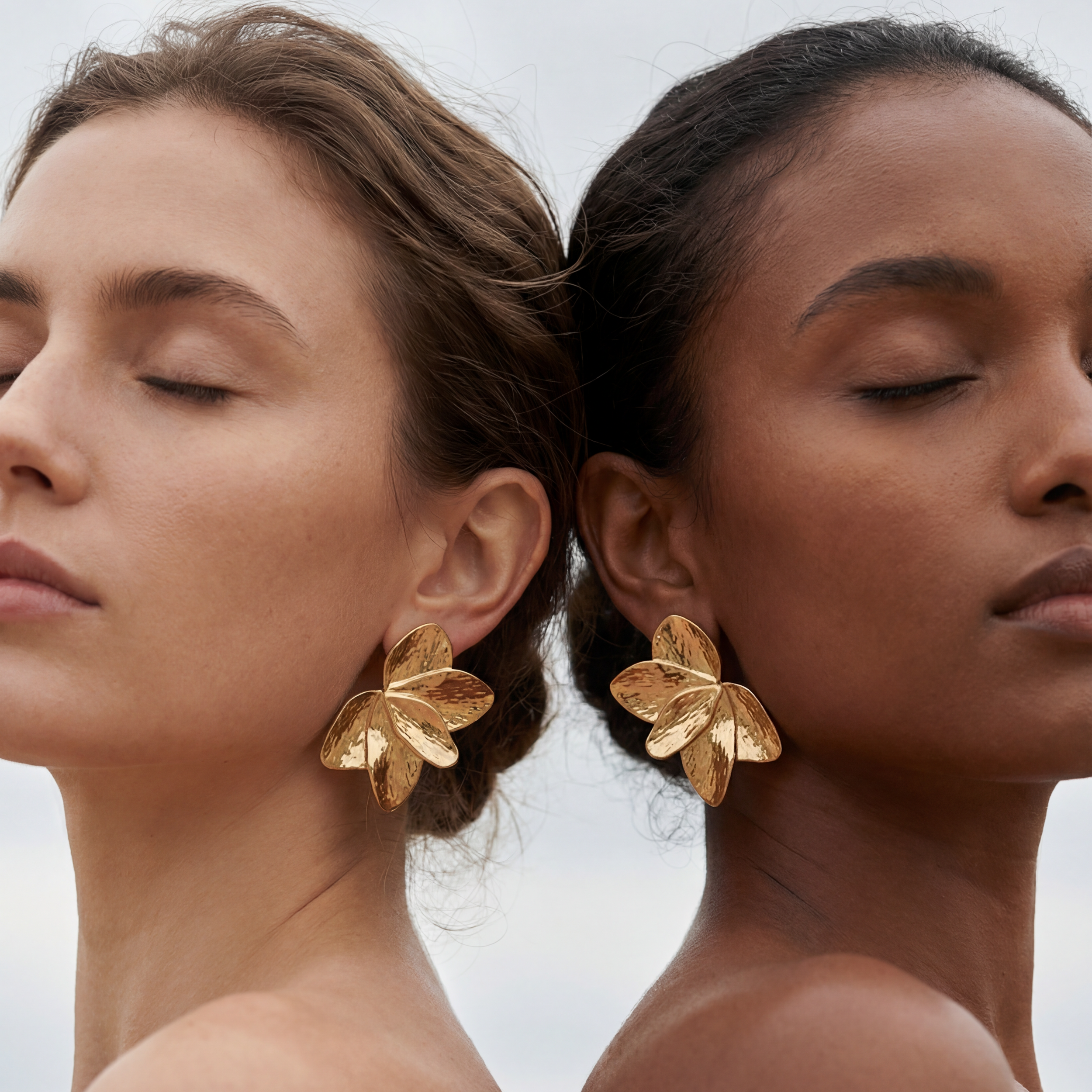 Two women wearing gold leaf earrings against a neutral background