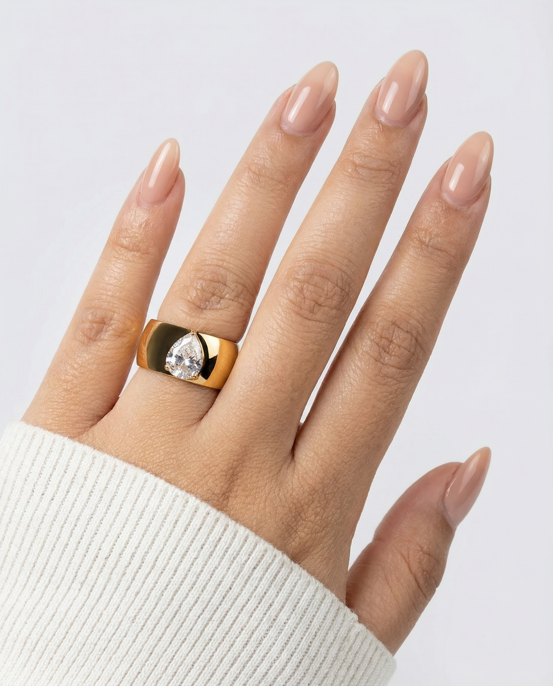 Gold ring with a diamond on a hand against a light gray background