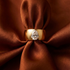 Gold ring with a diamond on a brown fabric background