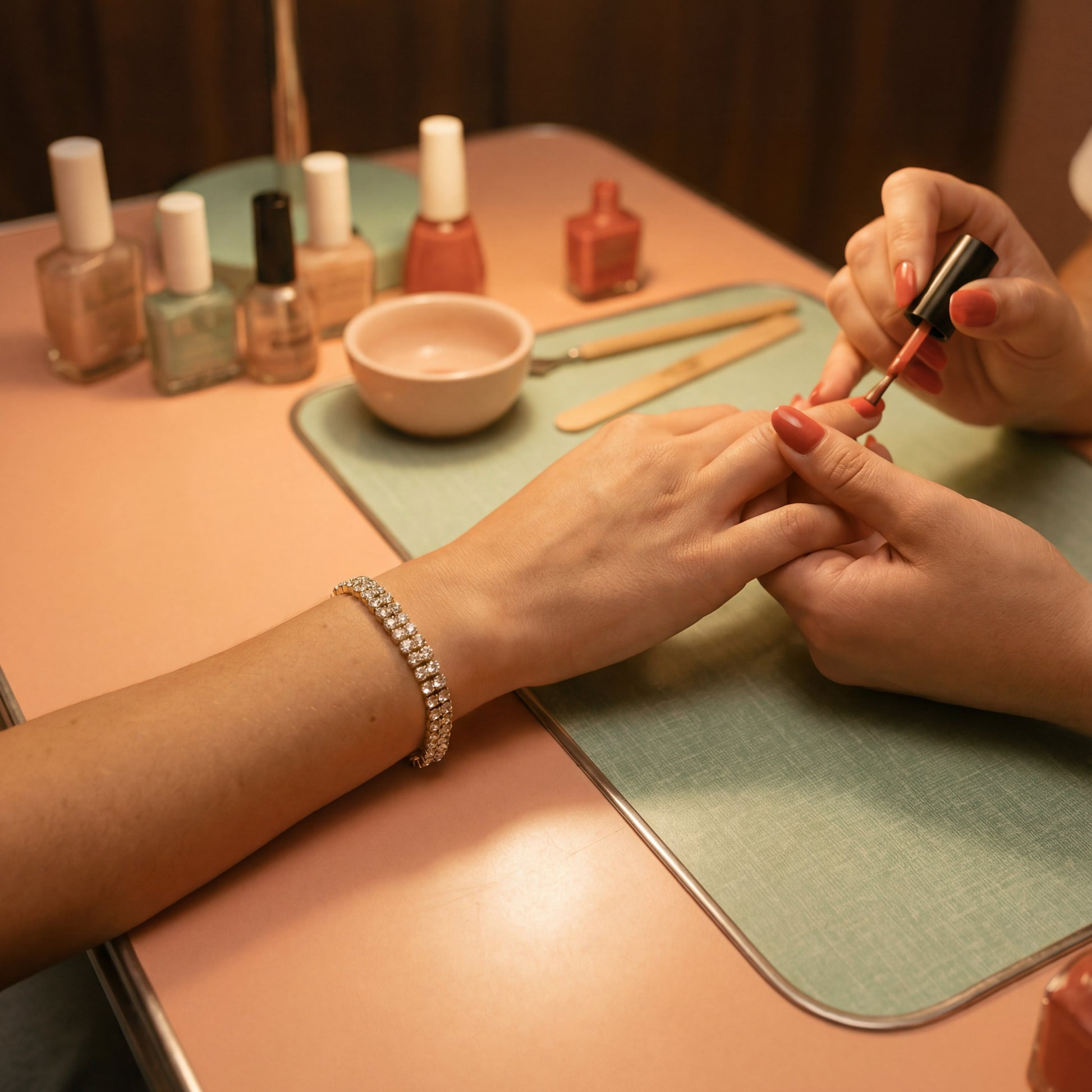 Person getting a manicure with nail polish bottles on a table.